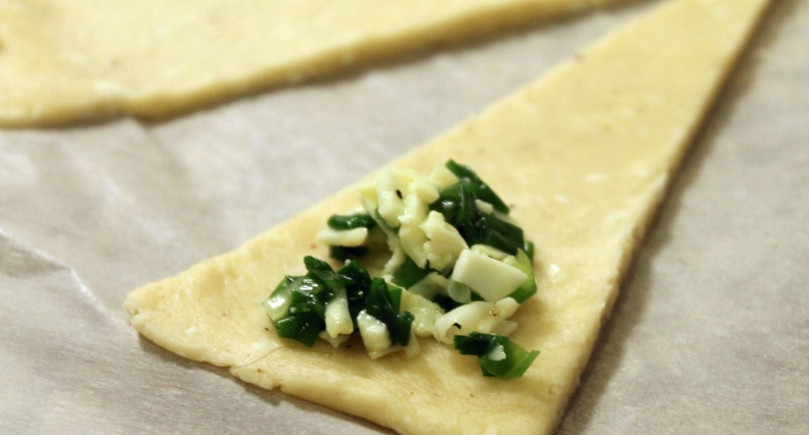 1. Этап. Рогалики с сулугуни: 2. Тесто раскатаем в тонкий пласт, вырезаем треугольнички, и на основание каждого вкладываем немного начинки. Сворачиваем рулетиком.