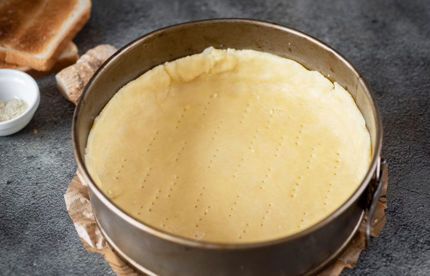 1. Этап. Пирог с патокой: Форму для выпекания застелите пергаментом для выпечки. Тесто распределите по дну, формируя основу для пирога с бортиками высотой примерно в 4 см.