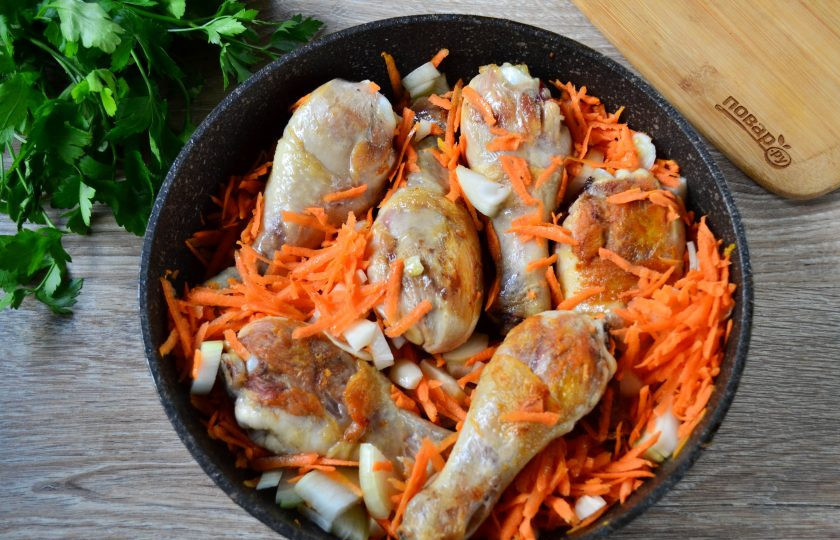 1. Этап. Куриные голени с луком и морковью: Когда голени обжарятся, отправьте в сковороду лук и морковь, добавьте соль и специи. Перемешайте и обжарьте в течение 5 минут, чтобы овощи слегка отмякли.