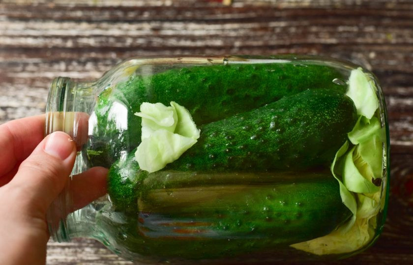 1. Этап. Огурцы с капустой на зиму: Выложите плотно вымытые огурцы и периодически добавляйте листики капусты.
