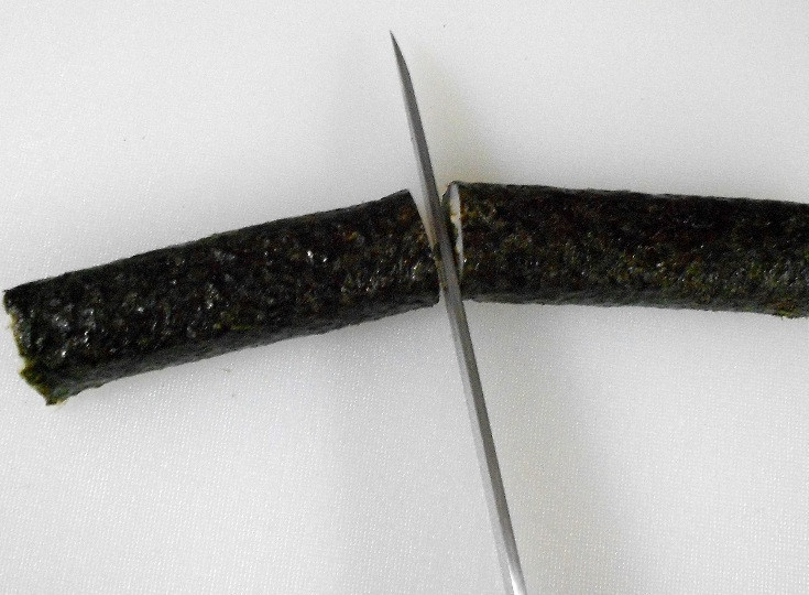 1. Этап. Роллы с угрем: Разрезаем готовый ролл на две части ножом, смоченным водой.