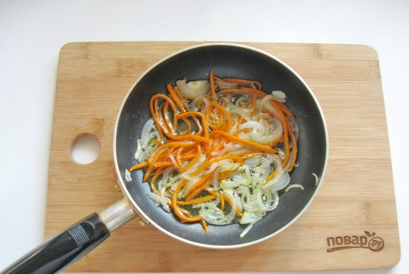 1. Этап. Кальмары с луком на сковороде: Налейте в сковороду подсолнечное масло и жарьте лук с морковью на небольшом огне 7-8 минут, периодически перемешивая.