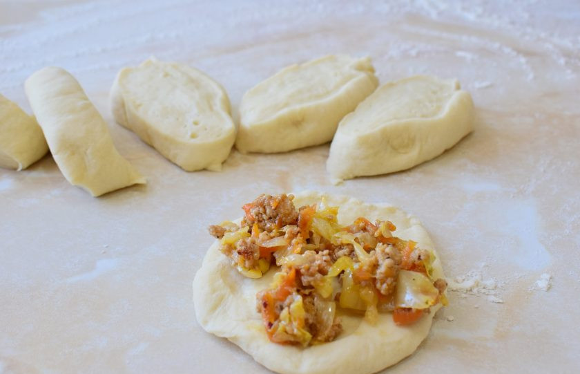 1. Этап. Бабушкины пуховые пирожки: Поделите тесто на части и наполняйте начинкой.