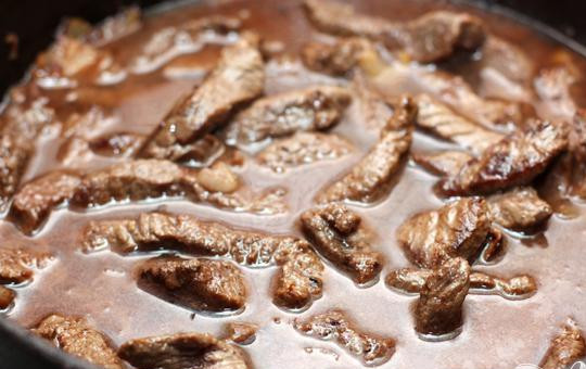 1. Этап. Тушеное мясо: 5. Доливаем в сковороду бульон или же кипящую воду так, чтобы почти все мясо было покрыто. Теперь все необходимо посолить, добавить специй и тушить под закрытой крышкой приблизительно около часа. Огонь должен быть не большой.