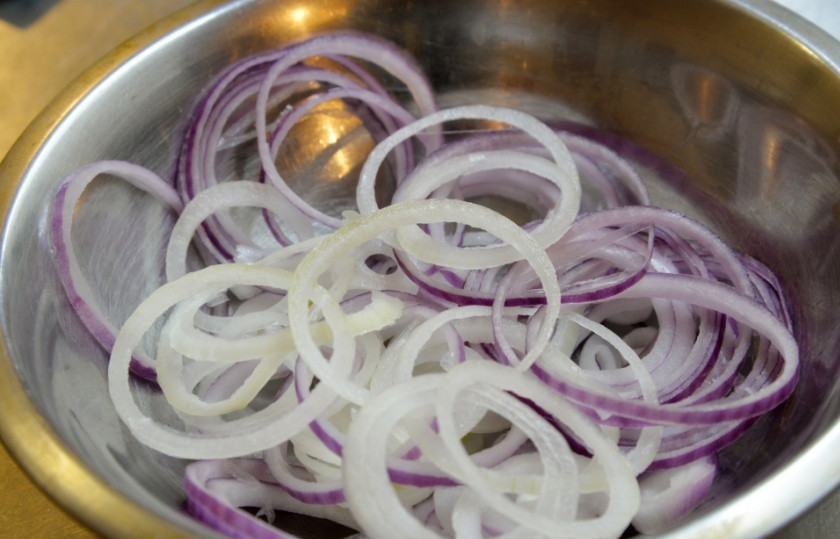 1. Этап. Рулетики из сельди в маринаде: Красный лук очистите, ополосните, а затем нарежьте кольцами. Слегка сбрызните его уксусом.