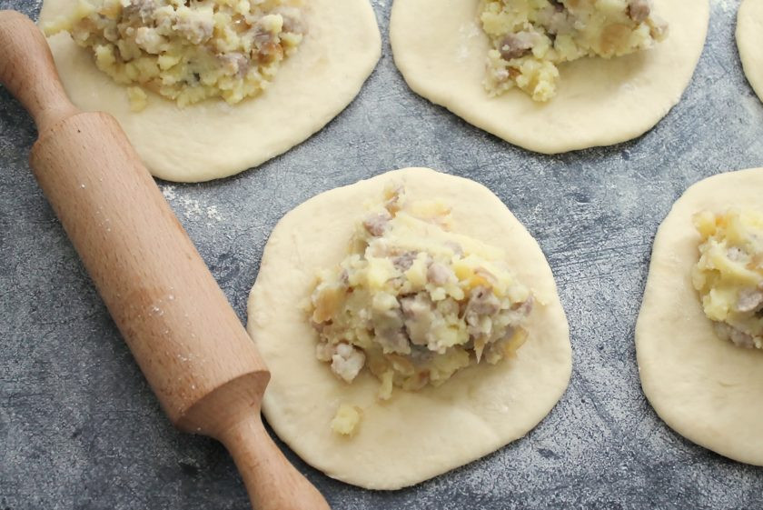 1. Этап. Пирожки с мясом и картошкой в духовке: Подошедшие шарики раскатайте в лепешки и разложите начинку.