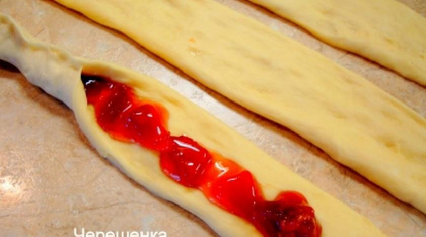 1. Этап. Пасхальная коса: Получилось отличное дрожжевое сдобное тесто, из которого вы можете выпекать все, что душе угодно… Это могут булочки, пышки, пироги и т.д. Но мы задумали пасхальную косу… Для этого тесто необходимо разделить на 3 равные части, каждую из которых сформировать в длинную полосу. А теперь на первую выкладываем варенье, смешанное с панировочными сухарями… Защипываем сверху тесто и получился вот такой рулетик…