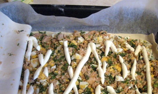 1. Этап. Пирог с красной рыбой из слоеного теста: Сверху выдавите из пачки майонез так, чтобы получилась сеточка. Вы можете заменить его на сметану, а можете просто заморозить масло и натереть его на терке поверх начинки.