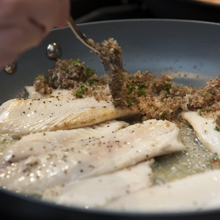 1. Этап. Жареная тилапия: 3. Жарьте рыбу в течение 3-4 минут с одной стороны, затем переверните и выложите на филе тилапии сверху смесь из панировочных сухарей и молотогоо ореха.