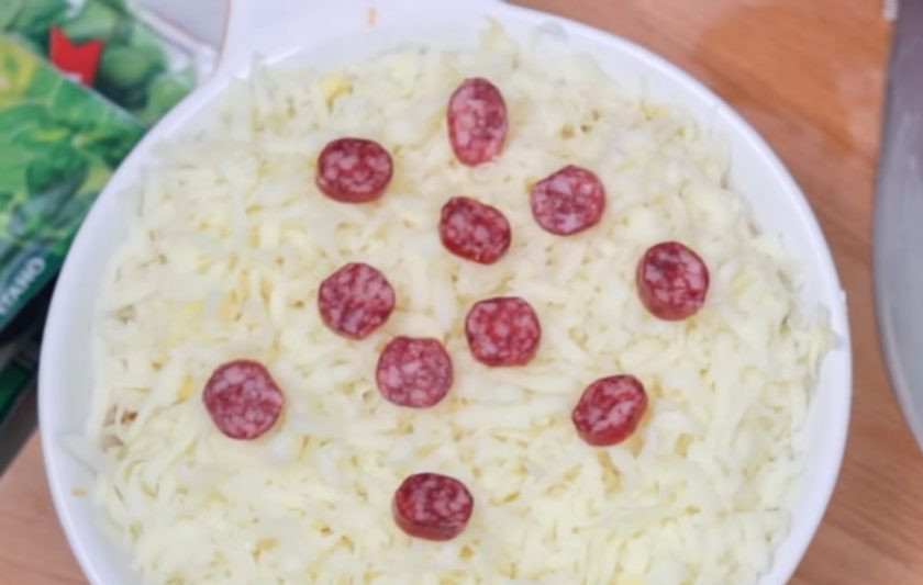 1. Этап. Пицца-соус с гренками: 2. Выложите сырную массу на дно формы для запекания и равномерно ее разровняйте. Затем смажьте сыр томатным соусом и посыпьте тертым сыром и моцареллой. Сверху добавьте нарезанную на тонкие кружочки колбасу.