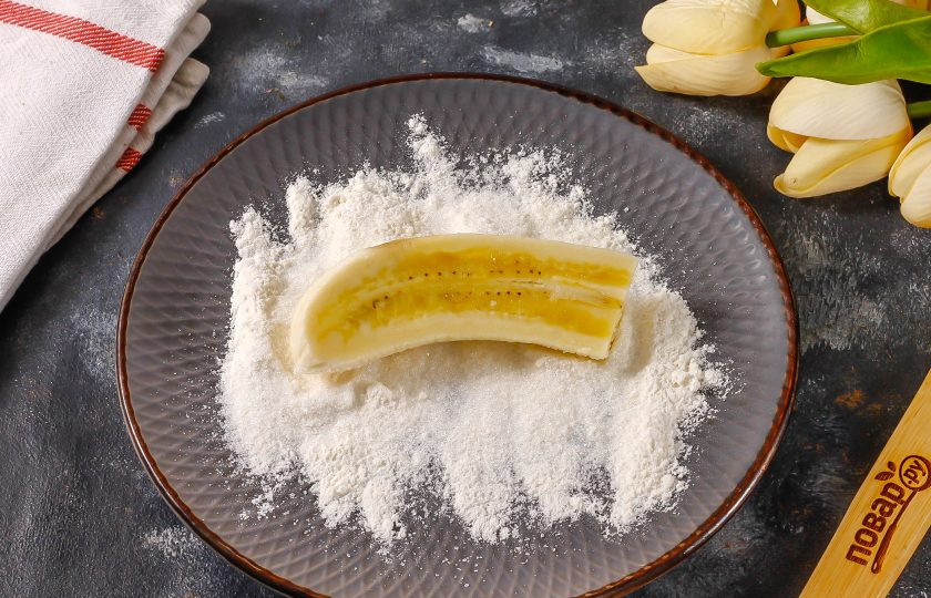 1. Этап. Жареные бананы в коньяке: Перемешайте сахар и пшеничную муку, высыпьте смесь на тарелку и обпанируйте в ней каждый банановый ломтик со всех сторон.