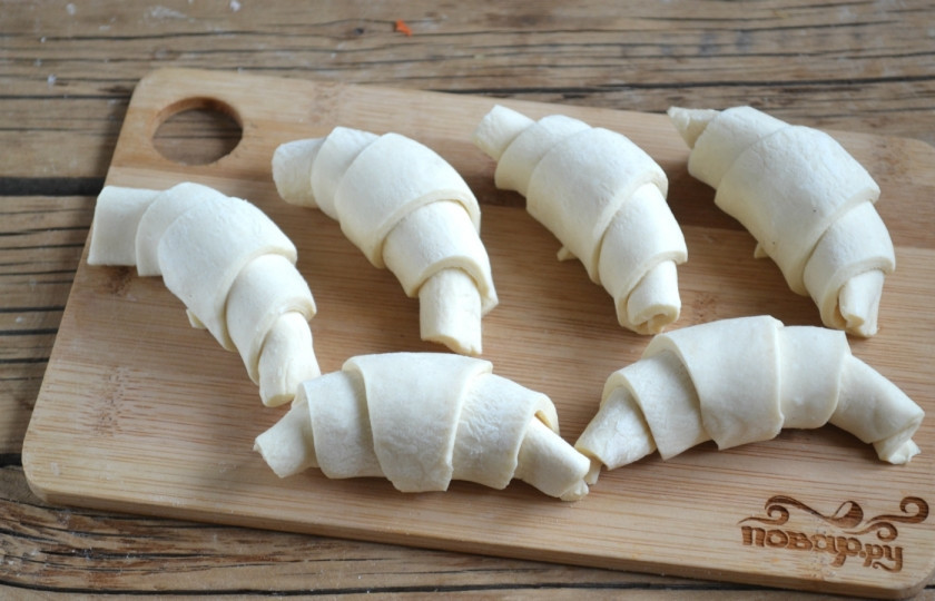 1. Этап. Круассаны из готового слоеного теста: Заверните треугольники в круассаны, придайте им форму полумесяцев.