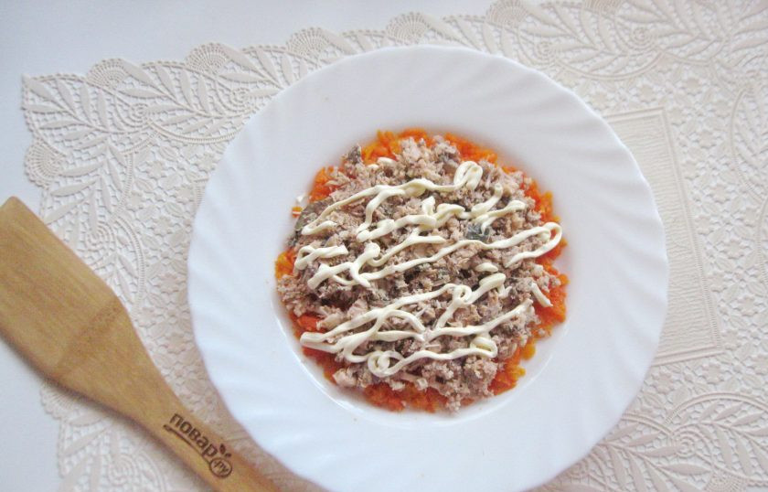 1. Этап. Салат с консервированной горбушей и грибами: Банку с консервированной горбушей откройте, жидкость слейте, а рыбу разомните вилкой. Выложите вторым слоем салата. Смажьте майонезом.