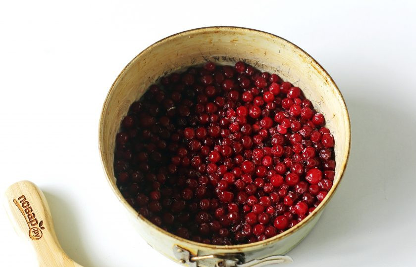 1. Этап. Бисквитный пирог с клюквой: Форму для запекания застелите пергаментом, смажьте сливочным маслом и распределите ровным слоем всю клюкву.