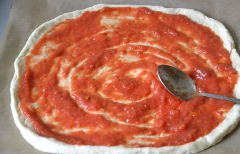 1. Этап. Пицца Суприм: Из теста сделайте большую тонкую лепешку, лучше это делать руками, не скалкой, нанесите томатный соус, тыльной стороной ложки разровняйте его.