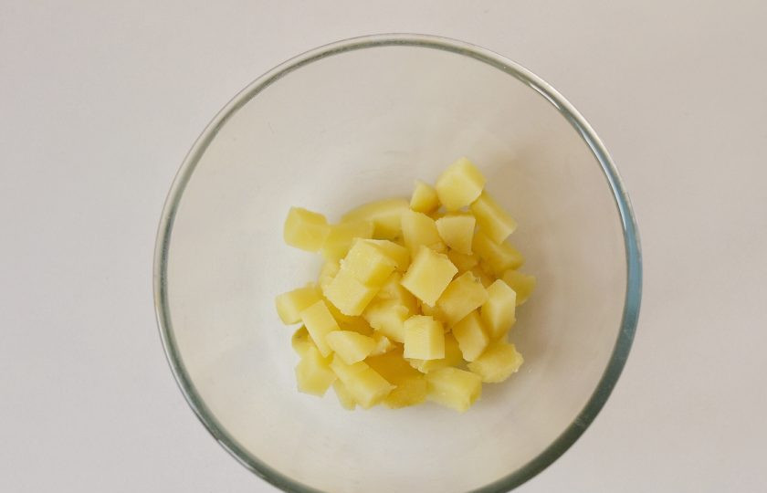 1. Этап. Салат с кукурузой, грибами и огурцами: Картофель помойте, отварите до мягкости. Очистите от кожуры и нарежьте кубиками.