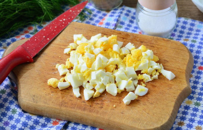 1. Этап. Салат с бужениной и кукурузой: Сварите куриные яйца вкрутую, затем остудите, почистите и нарежьте кубиками.