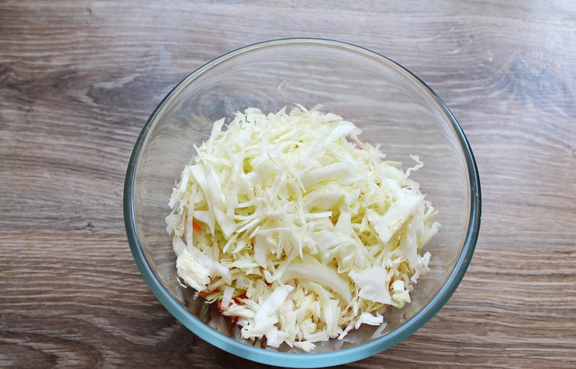 1. Этап. Салат с капустой и дайконом: У капусты отрежьте кочерыжку и тонко нашинкуйте. Выложите ее в миску с овощами.