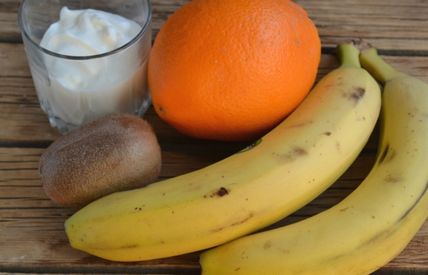 1. Этап. Торт из заварного теста с фруктами: Подготовьте фрукты. Бананы порубите кубиками, киви порежьте на пластины, а дольки апельсина нарежьте кубиками. Также приготовьте крем: смешайте сметану с сахаром, взбейте её миксером до загустения. Можно добавить 1 ст. ложку загустителя для сметаны, если крем слишком жидкий.