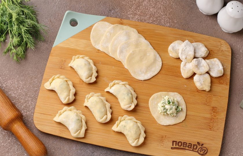 1. Этап. Вареники с адыгейским сыром и зеленью: От теста отрежьте кусок и сформируйте колбаску, нарежьте небольшими кусочками, а затем каждый кусочек обваляйте в муке и раскатайте в форме круга. Выложите по центру начинку и защипните края любым удобным способом.