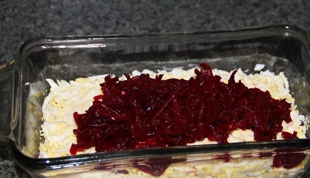 1. Этап. Салат рыбный: 5. Яйца натираю на крупной терке прямо в салатник, солю по вкусу и слегка прижимаю ложкой, смазываю щедро майонезом. Укладываю измельченную ранее свеклу.