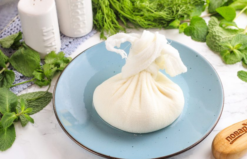 1. Этап. Домашний сыр Нежный: Соберите края марли в мешочек и завяжите. Подвесьте над раковиной и дайте стечь примерно 30-40 минут.