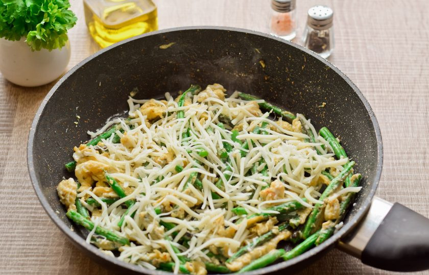 1. Этап. Спаржевая фасоль в яйце с сыром: Твердый сыр натрите и посыпьте фасоль.