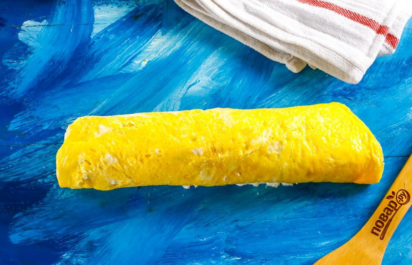 1. Этап. Рулет на год Крысы: Скрутите омлет рулетом, слегка прижимая, чтобы начинка равномерно распределилась. Поместите в холодильник и остудите.