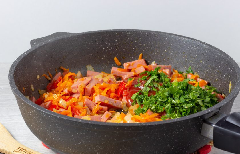 1. Этап. Поджарка из колбасы: В последнюю очередь добавьте томатную пасту и рубленную зелень. Перемешайте, посолите по вкусу и томите под крышкой 3-4 минуты.