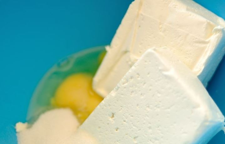 1. Этап. Сырники без жарки: Сразу включите духовку, чтобы она разогревалась до 180 градусов, пока вы подготавливаете тесто. Затем в миску вбейте сырые куриные яйца, добавьте к ним домашний творог или творог в брикетах, всыпьте сахар и перемешайте все ингредиенты.