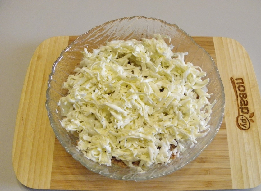 1. Этап. Салат Мимоза новогодний: Охлажденное сливочное масло натрите над салатником, старайтесь, чтобы оно ложилось равномерно.