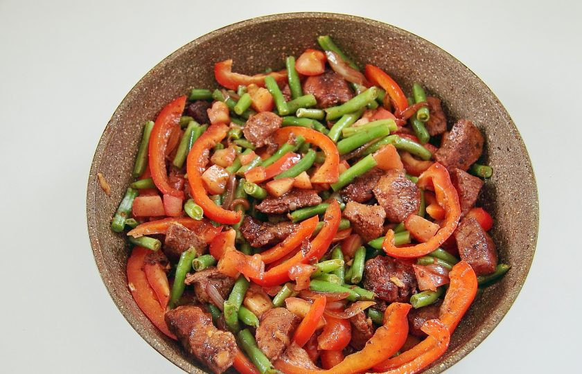 1. Этап. Жаркое из свинины и зеленой фасоли: Через пару минут добавьте фасоль, нарезанный соломкой болгарский перец и помидор без кожицы, нарезанный небольшими кубиками.