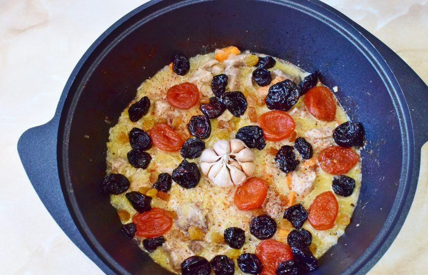 1. Этап. Плов праздничный: Поставьте в центр головку чеснока и выложите курагу, чернослив и изюм. Накройте крышкой и готовьте на малом огне 15-20 минут.