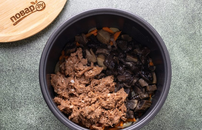 1. Этап. Гречка по-боярски в мультиварке: Грибы нарежьте на небольшие кусочки, а тушенку вилкой разделите на волокна. Добавьте в мультиварку и обжаривайте все вместе еще 4-5 минут.