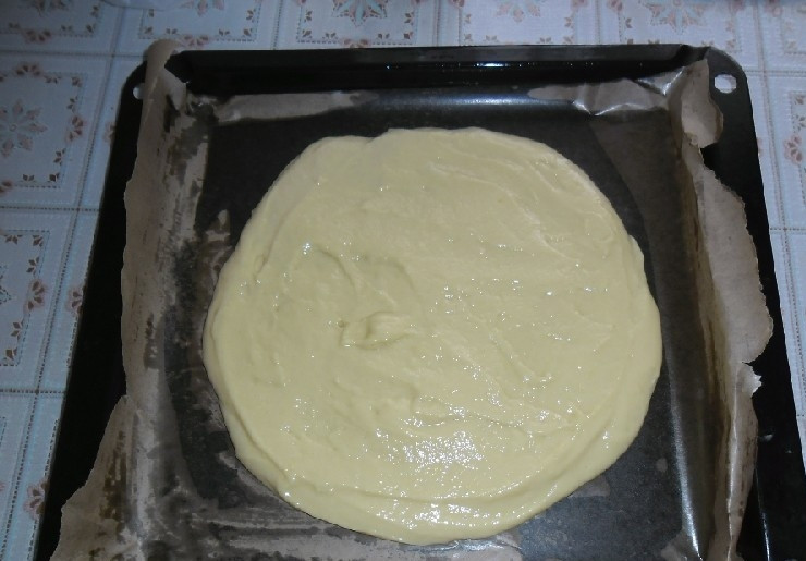 1. Этап. Легкий и вкусный тортик на кефире: Тесто выложите на противень с пергаментом в виде круга.