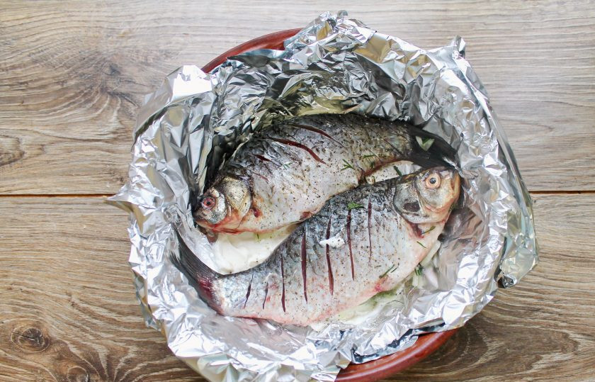 1. Этап. Караси в сметане в духовке в фольге: Форму застелите фольгой и выложите фаршированных луком карасей.