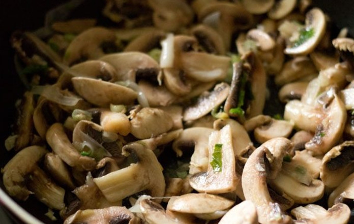 1. Этап. Рецепт супа с грибами: Добавьте к луку грибы, немного зеленого лука и жарьте, пока не выпарится почти вся жидкость.