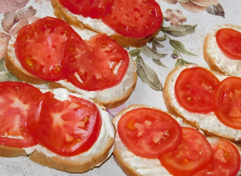 1. Этап. Чесночные бутерброды с яйцами и помидорами: Ломтики батона смажьте сырной пастой, а сверху разложите помидоры, нарезанные кружочками.