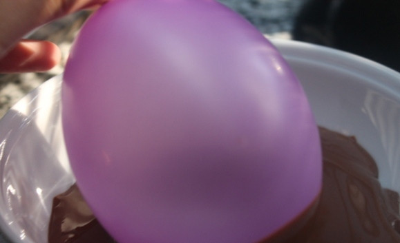 1. Этап. Шоколадные корзинки: 3. Растопим шоколад. Для этого поломайте шоколад на равные кусочки, подготовьте катрюлю с водой и большую миску для того, чтобы растопить шоколад на водяной бане. Следите за тем, чтобы кипящая вода не касалась миски с шоколадом, а ложка, которой мешаете, была сухой. Дайте шоколаду остыть (иначе шар лопнет!). Надуйте шарики и обмакните в шоколад. Выложите на бумагу для выпечки.