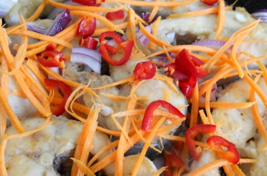 1. Этап. Тушеный пангасиус: Измельчите лук и перец, морковь натрите на терке. Добавьте к рыбе в сковороду.