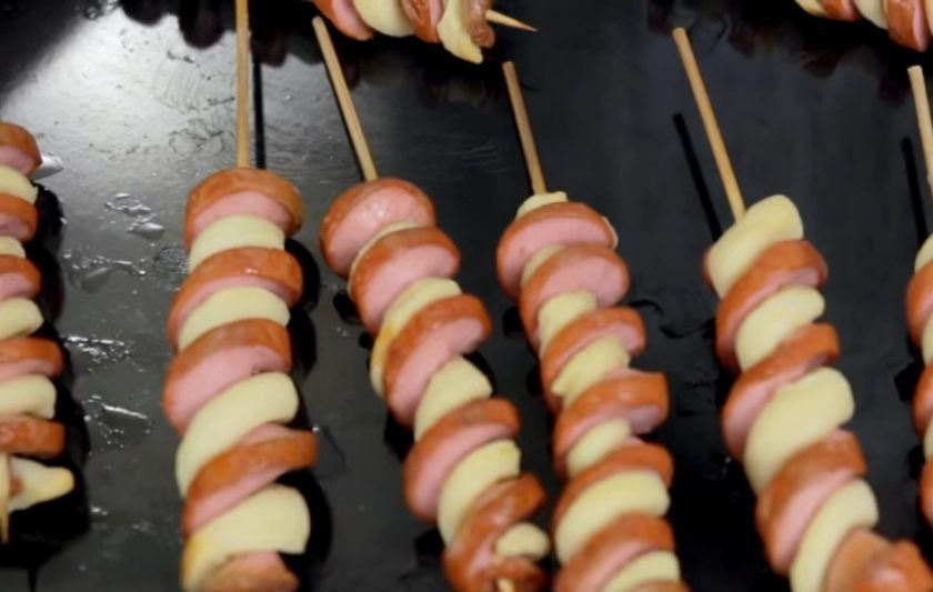 1. Этап. Торнадо-доги: 2. Слегка растяните сосиски на шпажках. Затем дрожжевое тесто разрежьте на полоски и обкрутите ими шпажку между сосисками. Выложите их на противень и выпекайте в разогретой до 180 градусов духовке в течение 15 минут.