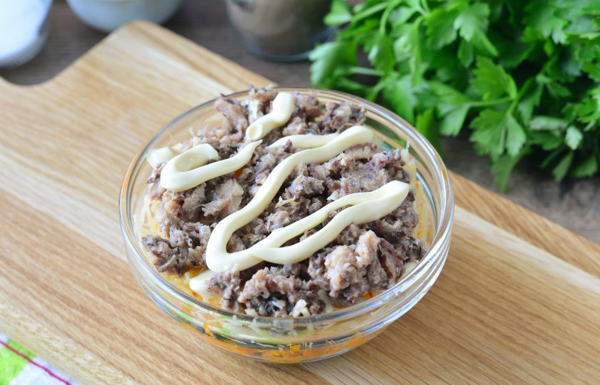 1. Этап. Салат с сайрой и грибами: Удалите крупные кости из консервированной сайры, разомните рыбу вилкой. Выложите консервы поверх сыра и полейте майонезом.