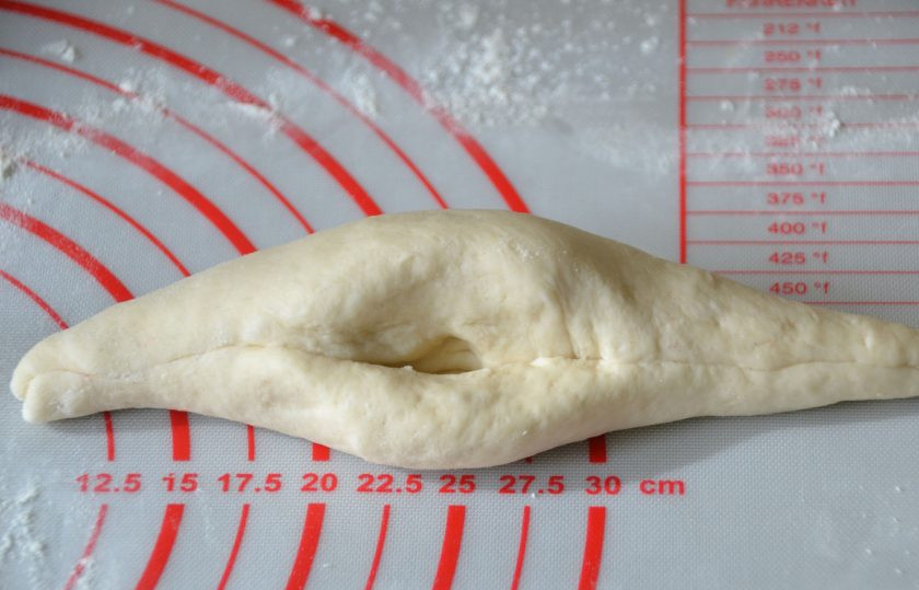 1. Этап. Булочки Римские чириолы: Захватите пальцами верх лепешки и движением к себе, захватывая одновременно нижний край лепешки, скатайте валиком, растягивая края в стороны. Чтобы в центре получился 