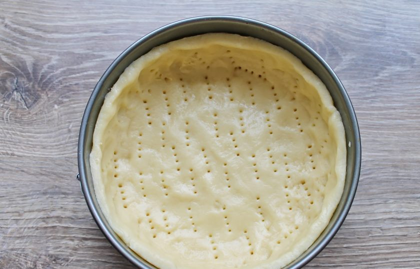 1. Этап. Цветаевский пирог с джемом: Возьмите форму диаметром 22-24 сантиметра и застелите дно бумагой для выпечки. Выложите тесто и равномерно распределите его по дну и бокам формы. Бортики должны быть примерно 3-4 сантиметра. Вилкой сделайте проколы по всей поверхности теста. Поставьте в горячую духовку и выпекайте в течение 10 минут.