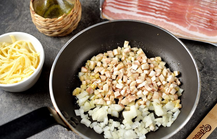 1. Этап. Шампиньоны в беконе в духовке: Нарежьте мелко репчатый лук и ножки грибов, быстро обжарьте в минимальном количестве растительного масла до мягкости, это будет начинка.