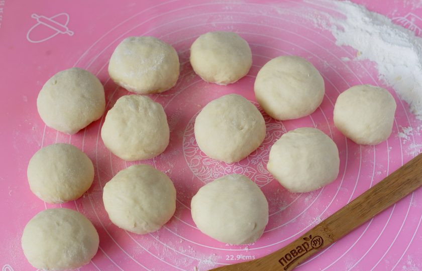 1. Этап. Булочки с курицей и сыром: Подошедшее тесто разделите на 10-12 частей. Сформируйте колобки, накройте их полотенцем и оставьте еще на 15-20 минут.