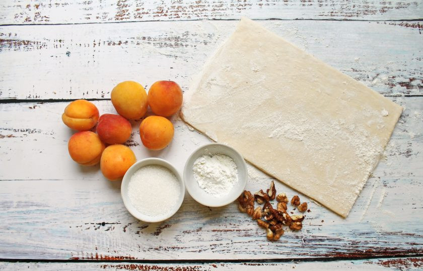 1. Этап. Слоеный пирог с абрикосами: Подготовьте все необходимые ингредиенты для приготовления слоеного пирога с абрикосами. Тесто достаньте заранее из морозилки, чтобы стало мягким. Абрикосы тщательно вымойте и обсушите.