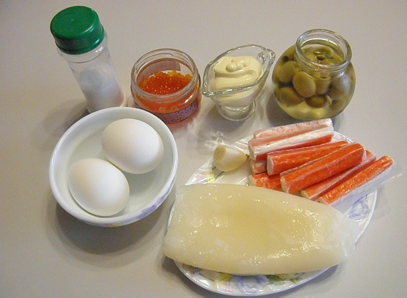 1. Этап. Салат с кальмарами самый вкусный: Приготовьте продукты для салата. Кальмар отварите в соленой воде ровно 1 минуту, достаньте его и охладите. Яйца отварите вкрутую. С палочек крабовых снимите обертки.