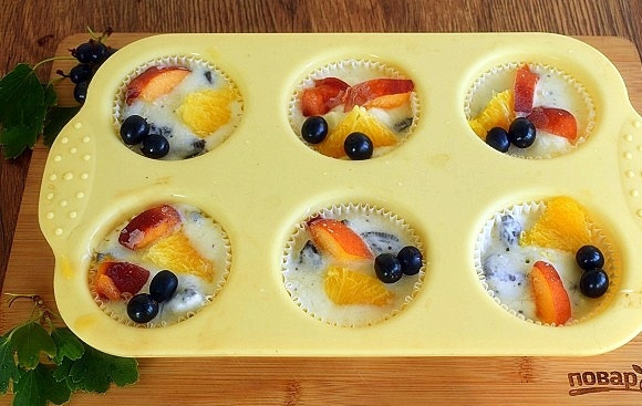 1. Этап. Пирожные Орео под йогуртом: Пергаментные корзиночки для кексов поместите в силиконовые формы, чтобы при наполнении они не потеряли форму. На дно каждой корзинки уложите по одному печенью. Йогурт перемешайте с кусочками оставшегося измельченного печенья, наполните этой смесью корзиночки. Сверху положите кусочки фруктов и ягоды. Поставьте в морозильник минимум на 4 часа.