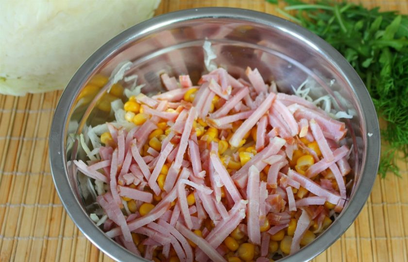 1. Этап. Салат с кукурузой, капустой и колбасой: Вареную колбасу или ветчину нарезаем тонкими полосками и высыпаем в салат.